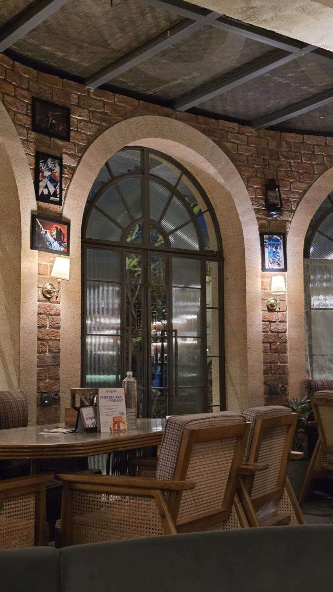 Brick arches and framed pictures over cane chairs in the evening