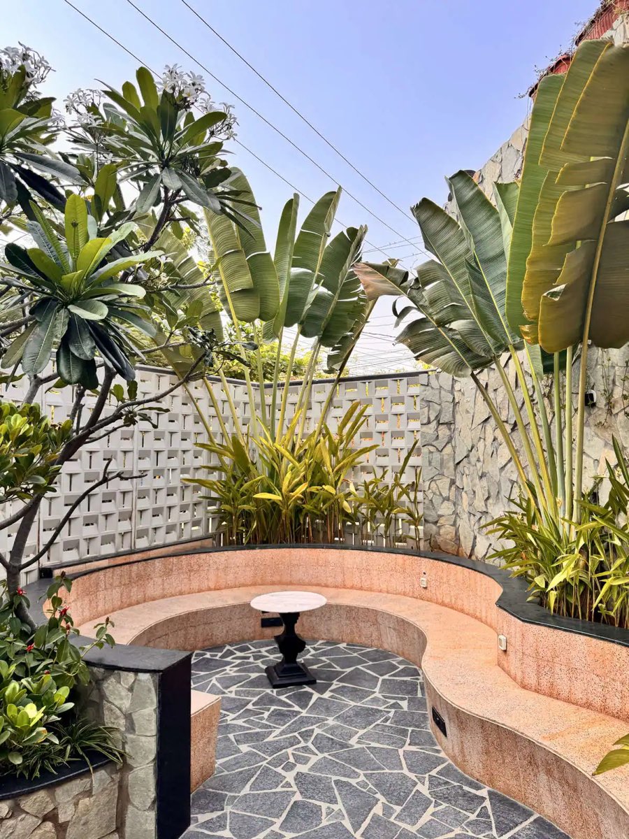 Courtyard with plumeria trees, terrazzo bench and breeze-block wall