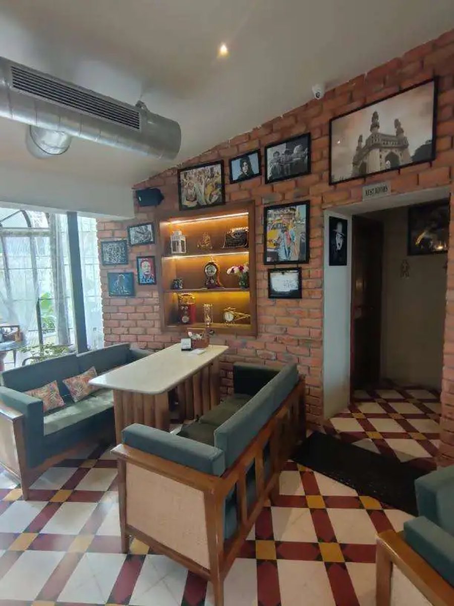 Lounge seating on chequered tile with framed photographs on brick