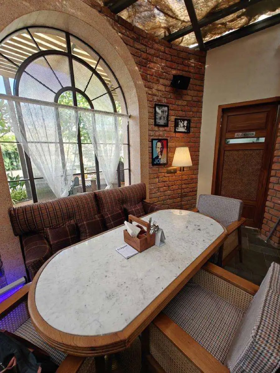 Arched window with lace curtains above a plaid banquette